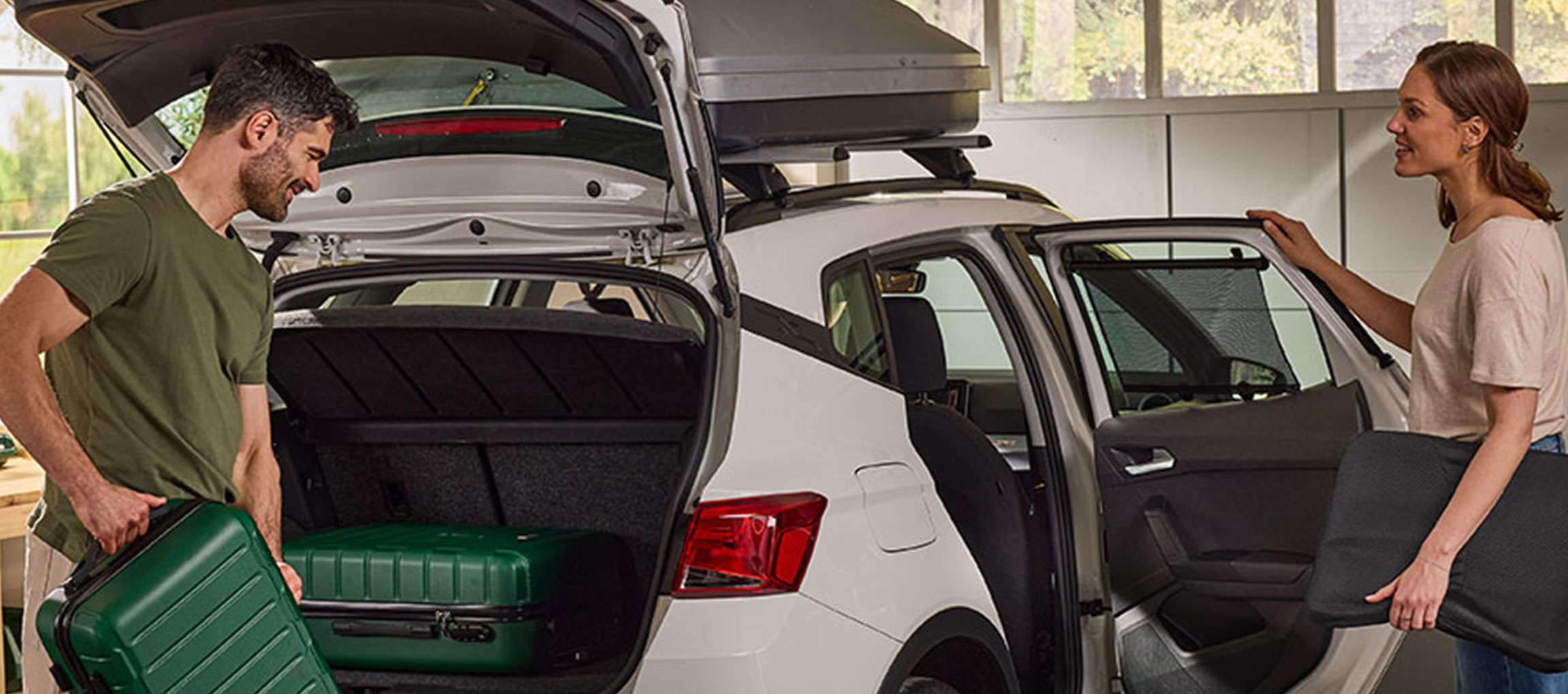 Man and woman loading suitcases and car accessories into a car.