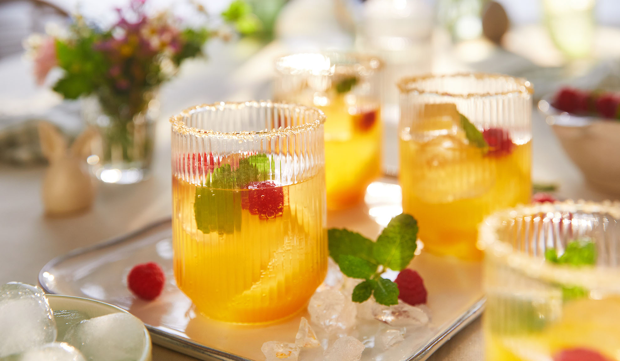 Refreshing summer drinks with raspberries and mint, served on a tray with ice.