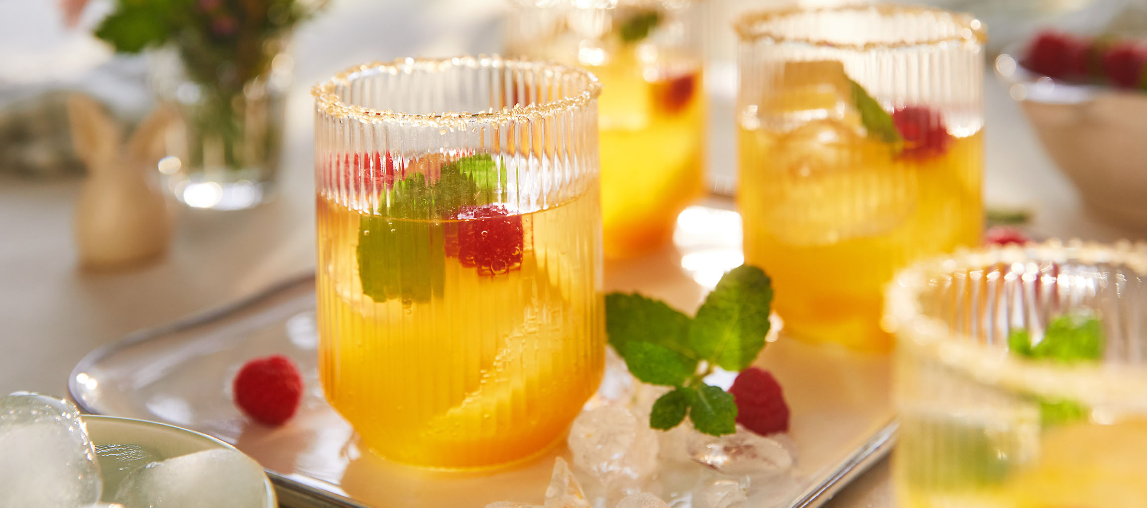 Glasses of refreshing drink with raspberries and mint, served on a tray.