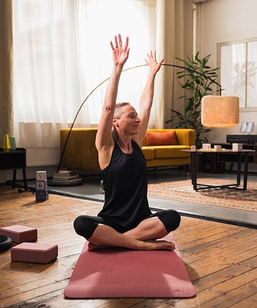 Woman practicing yoga with blocks and mat.