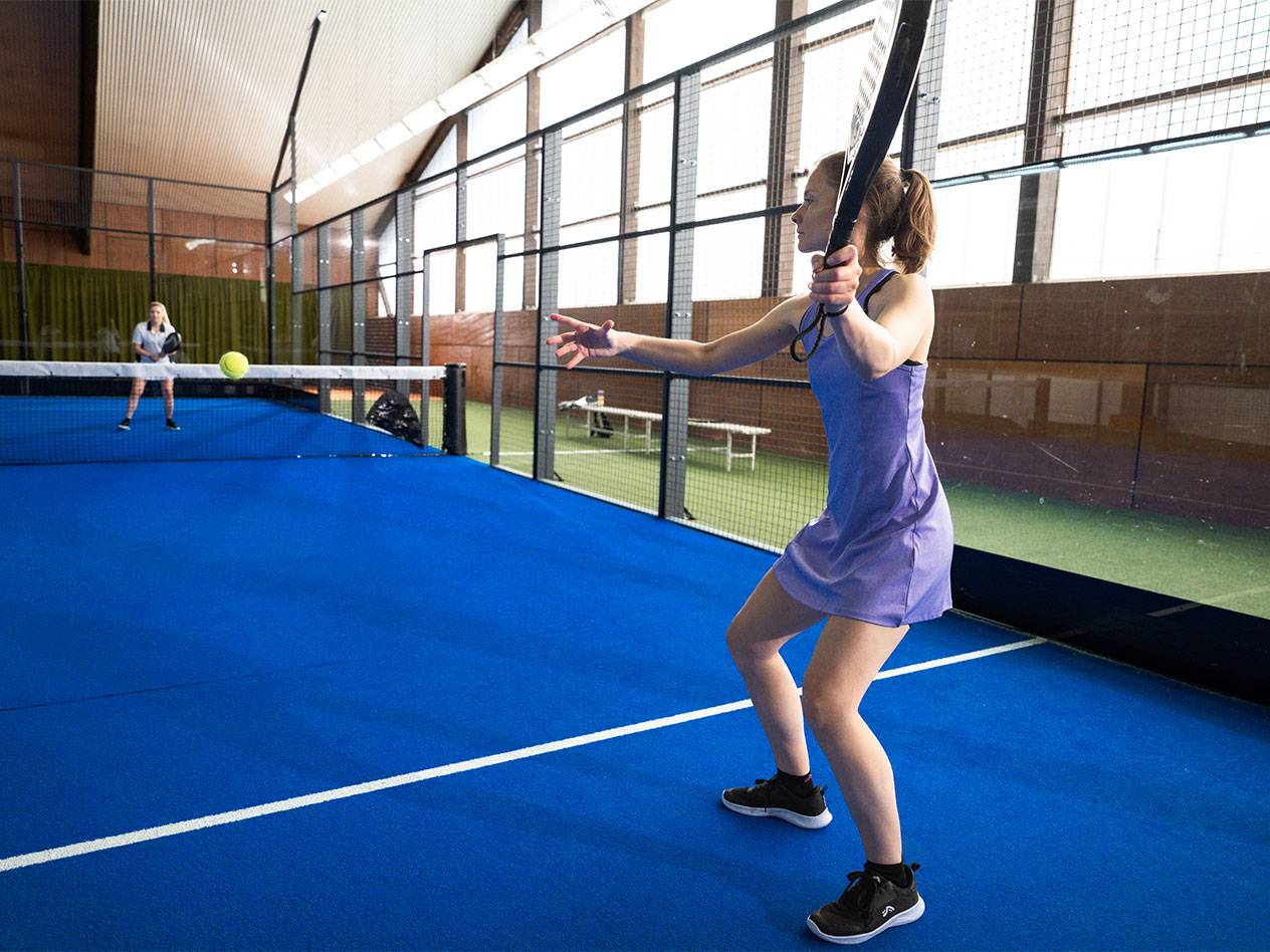 Lana Büttner plays padel on a blue court in a purple dress.