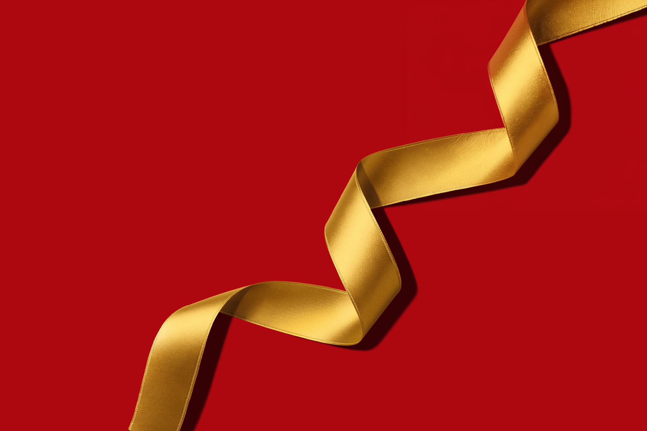 A flowing gold ribbon on a solid red background.