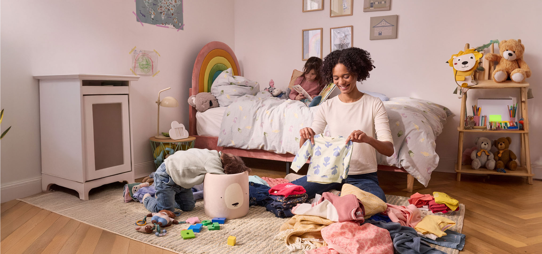 A mother organizes children's clothes in a kid's room.