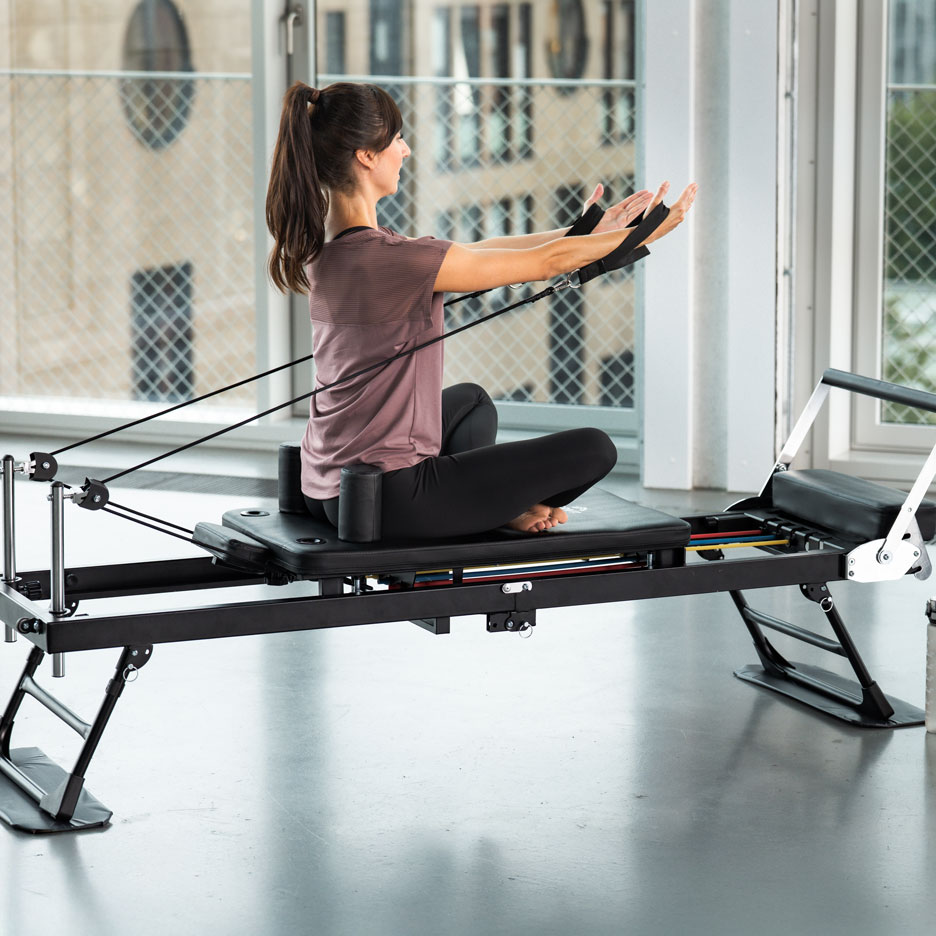 Woman exercising on a pilates machine with resistance bands.