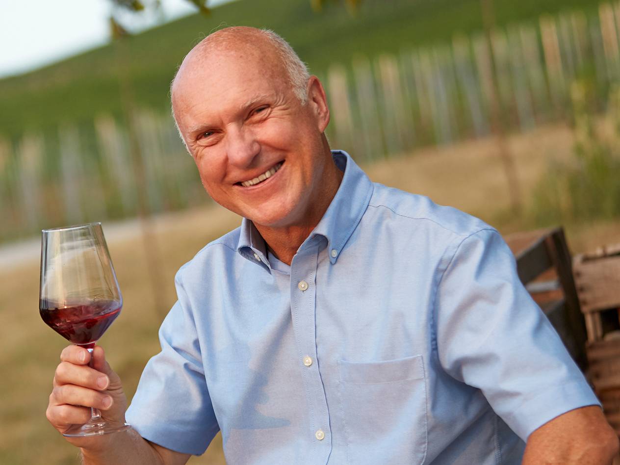 Man in vineyard enjoying red wine.