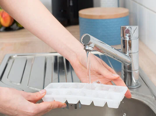 Filling an ice cube tray with water.