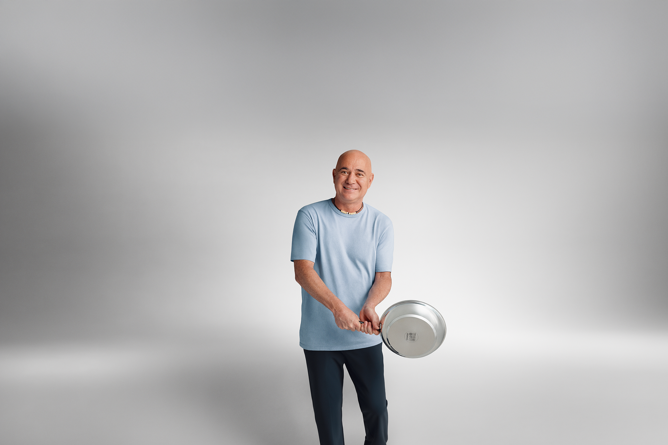 Andre Agassi in a blue T-shirt holding a pan.