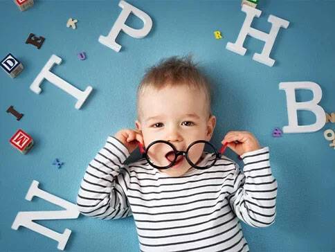 Baby with glasses and alphabet blocks.