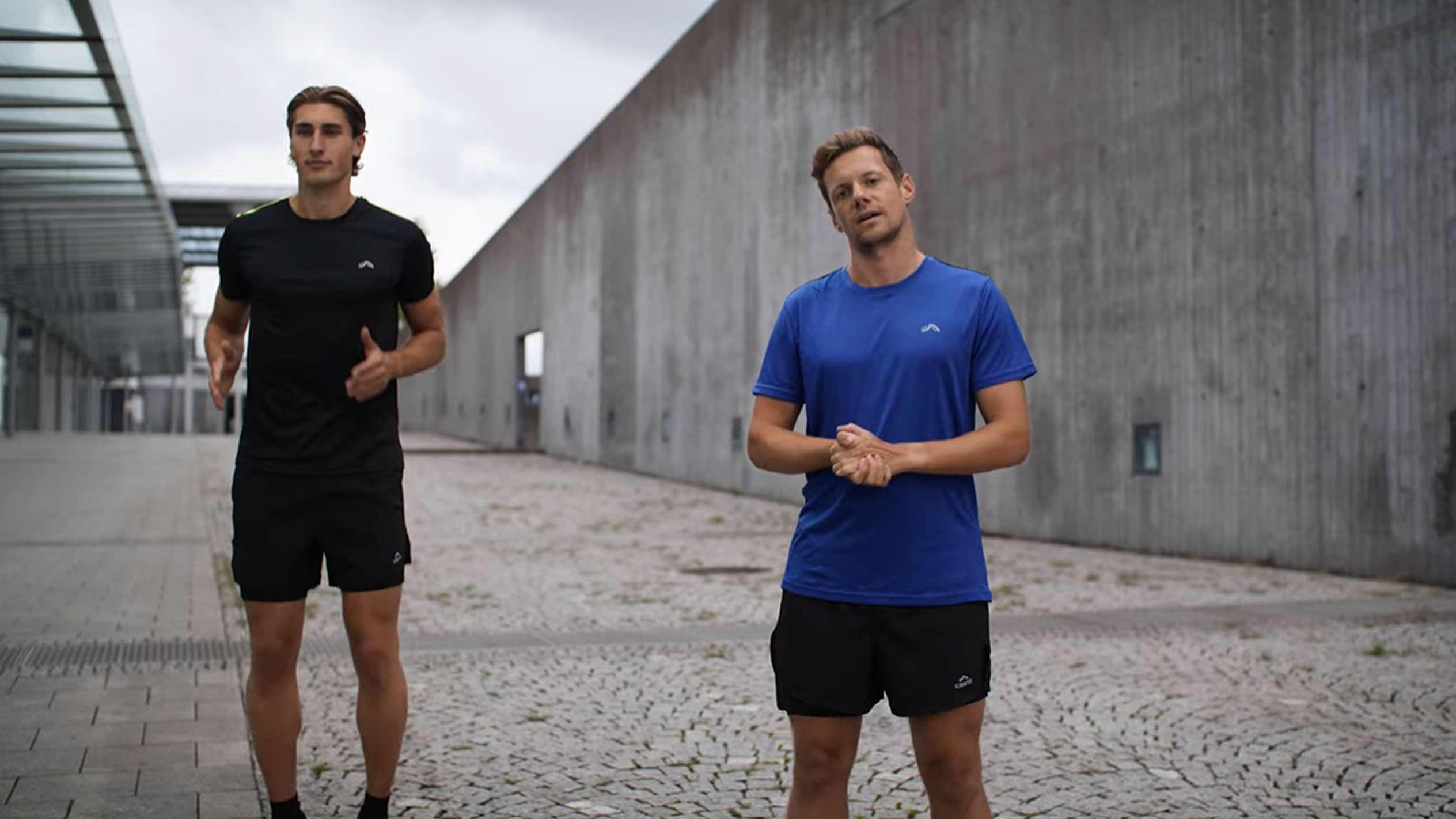 Two men in black and blue sportswear outdoors.