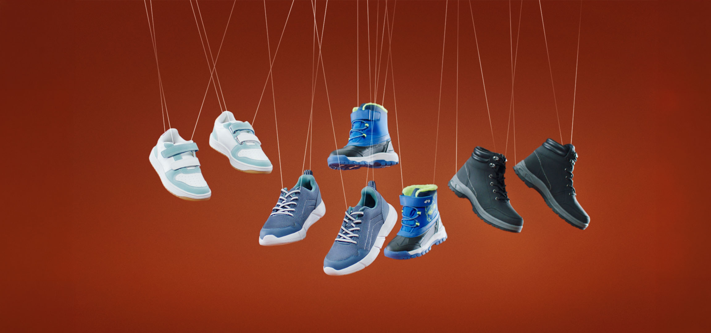Various children's shoes, including sneakers and boots, hanging from strings.