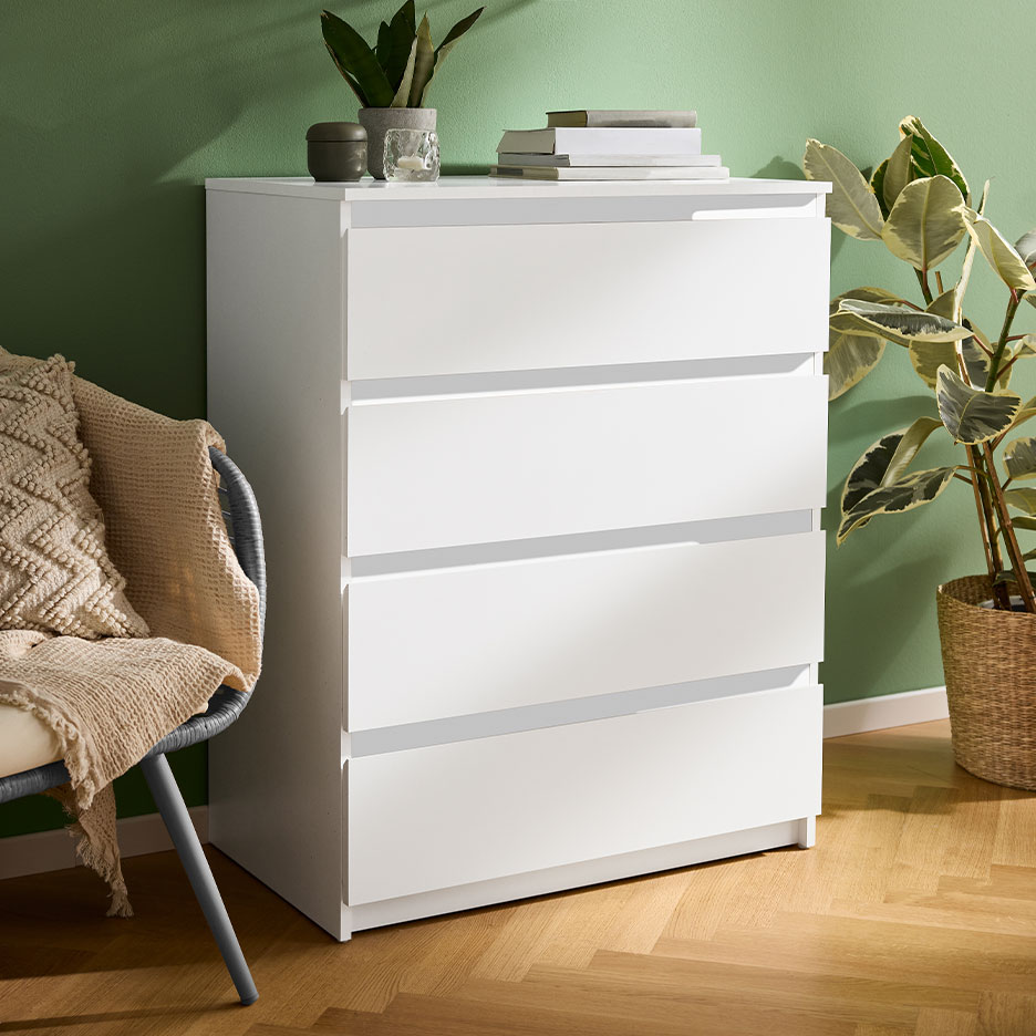 White four-drawer dresser in a room with green walls and a wooden floor.