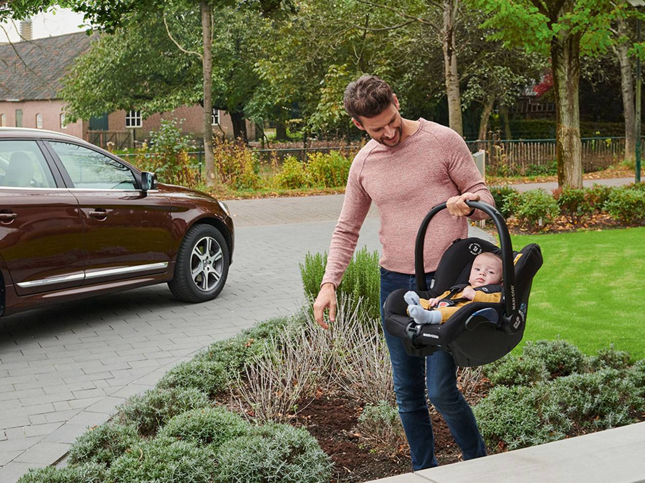 Father carrying a Maxi-Cosi baby car seat.
